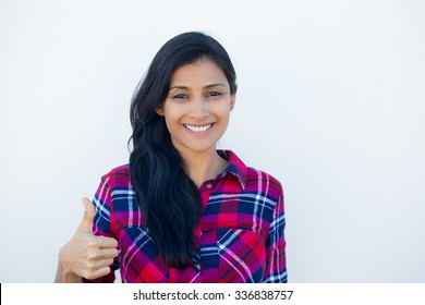 Closeup portrait of young pretty woman with one thumbs up sign gesture, plaid red shirt, isolated white wall background. Positive emotion facial expression feelings, signs and symbols, body language