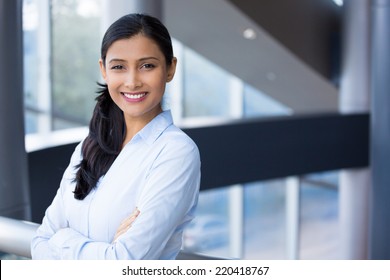 Closeup Portrait, Young Professional, Beautiful Confident Woman In Blue Shirt, Arms Crossed Folded, Smiling Isolated Indoors Office Background. Positive Human Emotions