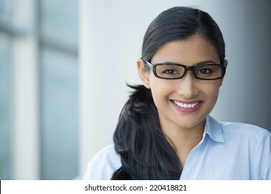 Closeup Portrait, Young Professional, Beautiful Confident Adult Woman In Blue Shirt, With Black Glasses, Smiling Isolated Indoors Office Background. Positive Human Emotions