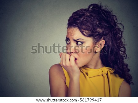 Closeup portrait young scared nervous woman biting her fingernails craving for something or anxious isolated on gray background. Negative human facial expression feeling