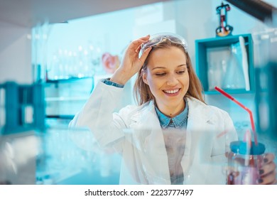 Close-up portrait of young scientist smiling. Confident female researcher is wearing protective eyewear. She is in science laboratory. State of the art science equipment.