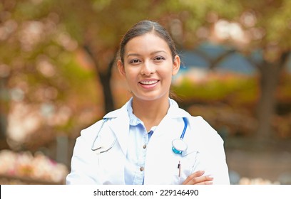 Closeup Portrait Young Smiling Confident Female Doctor Healthcare Professional Isolated Outside Indian Fall Trees Background. Patient Clinic Visit Health Care Reform. Positive Emotion Face Expression