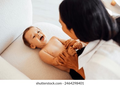 A close-up portrait of a young smiling woman and her sweet baby. A charming mom is playing with her little child. Mother and son laugh and have fun together at home. - Powered by Shutterstock