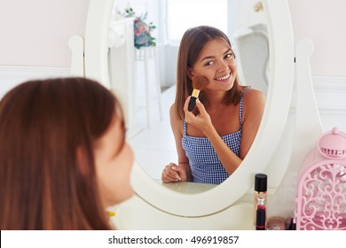 Close-up portrait of young stylish girl applying a powder on the face using makeup brush