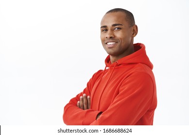 Close-up portrait of young successful african-american adult man in red hoodie, cross arms on chest turn head to camera with satisfied smile, looking confident and reliable, white background