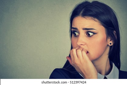 Closeup portrait young unsure hesitant nervous woman biting her fingernails craving for something or anxious isolated on gray wall background. Negative human emotions facial expression feeling