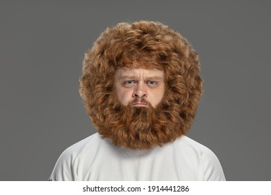 Close-up portrait of young very hairy man isolated over grey background.