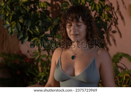 Close-up portrait of a young woman with curly dark hair meditating in a low light setting