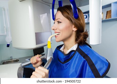 Closeup portrait young woman having panoramic digital X-ray of her teeth, isolated background dentist office. 