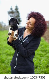 Closeup Portrait Of A Young Woman Holding A Baby Goat Outdoor