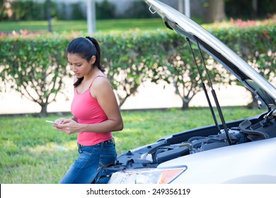 Closeup Portrait, Young Woman In Pink Tanktop Having Trouble With Her Broken Car, Opening Hood And Texting For Help On Cell Phone, Isolated Green Trees And Shrubs Outside Background