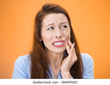 Closeup Portrait Young Woman With Sensitive Tooth Ache, Crown Problem Crying From Pain, Touching Outside Mouth With Hand Isolated Orange Background. Negative Emotion, Facial Expression Feeling, Health