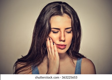 Closeup Portrait Young Woman With Sensitive Toothache Crown Problem About To Cry From Pain Touching Outside Mouth With Hand Isolated On Gray Background. Negative Human Emotion Face Expression Feeling