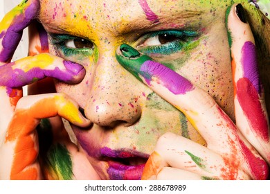 Close-up portrait of young woman with unusual makeup. Model posing with paint drops over her face. Creative makeup.