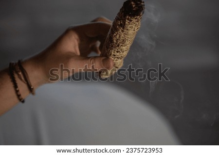 Close-up portrait of a young woman's hand holding smoking smudge stick