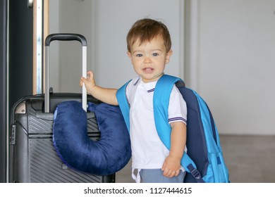 Close-up Portrat Of Cute Smiling Little Baby Boy With Big Backpack And Suitcase With Travelling Pillow Stay Near Open Door Ready To Leave, Prepared For Travel. Traveling With Child Concept