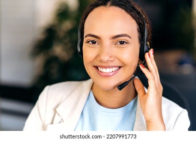 Close-up Of Positive Confident Hispanic Or Brazilian Woman, With Headset, Call Center Agent, Support Service Operator, Sits In The Office, Consult Clients Online, Looking At Camera, Smiling Friendly