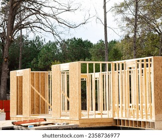 Close-up post, beam and timber framing new suburban wooden house with OSB Oriented Strand Board plywood sheathing Flowery Branch, suburbs Atlanta, Georgia. Traditional American building development - Shutterstock ID 2358736977