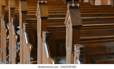 Close-up of posts of the backrests of benches in rows one behind the other in a diagonal view from the front made of wood in a church in Germany