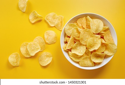 Close-up of potato chips or crisps in bowl against yellow background - Shutterstock ID 1450321301