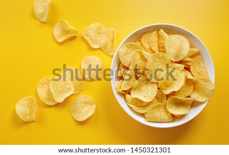 Close-up of potato chips or crisps in bowl against yellow background