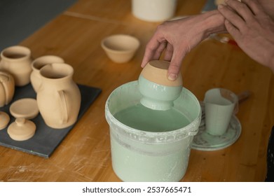 Close-up of a potter's hands glazing a pottery piece.  - Powered by Shutterstock