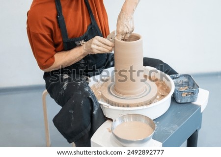 Similar – Young female sitting by table and making clay or ceramic mug