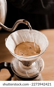 Close-up pour over filter with ground coffee in the funnel in focus. Drip filter coffee brewing. Pour over alternative method of pouring water over roasted and ground coffee beans contained in filter - Shutterstock ID 2273942421