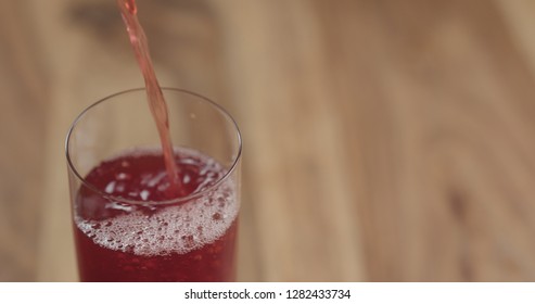 Closeup Pouring Cranberry Juice Into The Glass On Wood Table