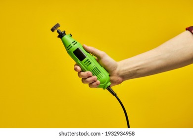 Close-up Power Tool. Green Die Grinder In Hands Isolated On Yellow Background. Household Carpentry And Repair Concept