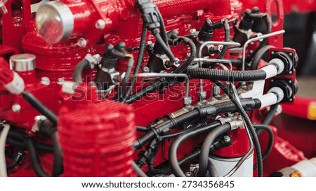 Close-up of a powerful red combustion engine showing complex network of pipes and wires