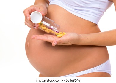 Close-up Of Pregnant Belly With Prenatal Vitamins. Tablets, Pills  During Pregnancy.