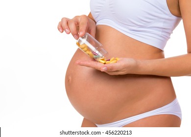 Close-up Of Pregnant Belly With Prenatal Vitamins. Tablets, Pills  During Pregnancy.