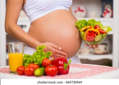 Close-up of a pregnant belly. Women's Health, fortified food. Fresh vegetables, diet and figure