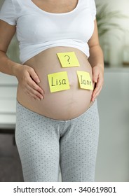 Closeup of pregnant woman choosing baby name on the stomach - Shutterstock ID 340619801