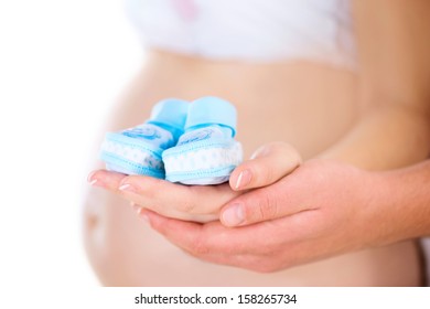 Close-up of a Pregnant Woman and her Husband holding Baby Shoes in their Hands. Mom and Dad Expecting Baby boy. Pregnant Woman Belly. Pregnancy. Baby Shower