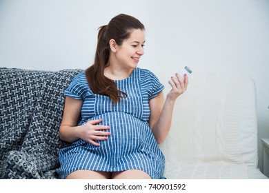 Close-up Of Pregnant Woman Reading Vitamin Pills Prenatal Medications. Baby Birth Preparations