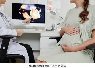 Close-up Of Pregnant Woman Sitting On Chair And Listening To Doctor Talking About Condition Of Baby Pointing At Ultrasound Image On Monitor