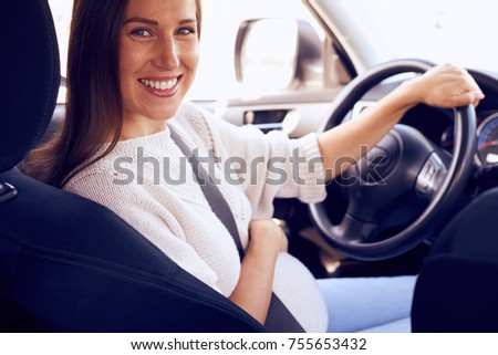 Closeup of pregnant woman turning to camera while sitting at wheel 