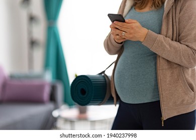 Closeup of pregnant woman and yoga mattress, preparing to go to class. 