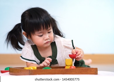 Closeup: A Preschool Little Girl 2-3 Years In Montessori Classroom Deep Concentration Engaged Stacking Sensory Wooden Blocks. Hands On Activity, Tools, Child Development, Learn Through Play Concept.