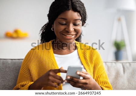 Closeup of pretty black lady using modern smartphone