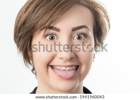 close-up of pretty dark haired teenage girl with braces sticking out her tounge
