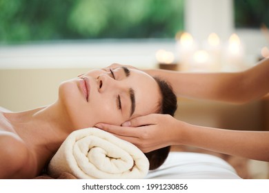 Close-up of pretty woman lying on bed and getting massage from therapist