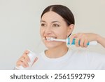 Close-up of a pretty young Caucasian woman brushing her teeth with a portable irrigator and an electric toothbrush at the same time. Oral care.