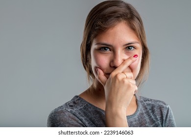 closeup pretty young woman hides her mouth behind a gesture of someone reflecting intensely; she has either missed something or just had a disruptive idea that she does not intend to share before maki - Shutterstock ID 2239146063