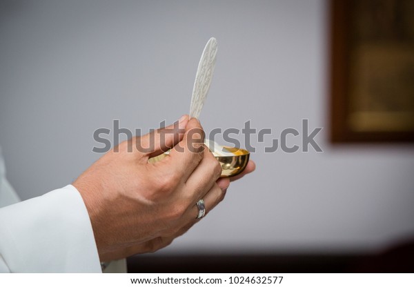 Closeup of priest with communion in the hand.\
Religious ceremony. Holy communion on a catholic mass. Concept:\
Free from sins.