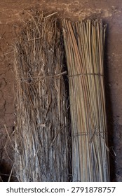 Close-up primitive grass and juncus rush mats leaning against interior adobe wall of hut