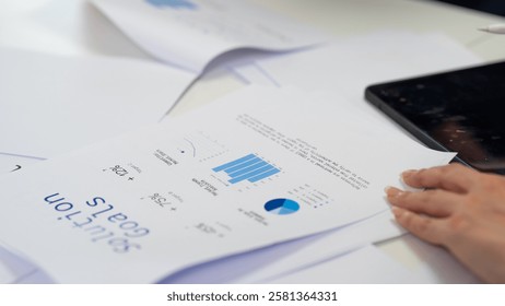 A close-up of printed reports with graphs and data analysis, alongside a person's hand, indicating data examination.