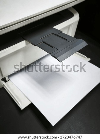 Close-up of a printer paper output tray with blank white sheet, modern office equipment detail.